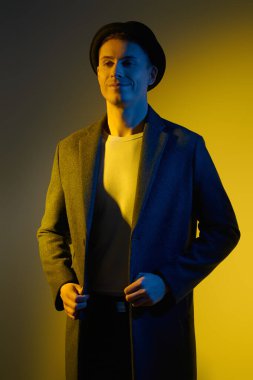 Zarif ceketli yakışıklı bir genç adam portresi ve stüdyoda karışık ışıkta poz veren bir şapka. Erkek güzelliği, moda. Yaşam tarzı. Hippi adam.. 