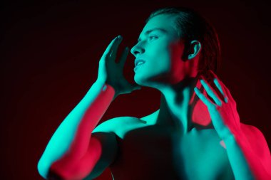 Kırmızı ve yeşil ışıkta çıplak bedeniyle poz veren yakışıklı bir genç adamın sanat portresi. İnsanın güzelliği ve sağlığı. Resim..