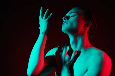 Şehvetli, yakışıklı, atletik kaslı, siyah arka planda poz veren, yeşil ve kırmızı ışık saçan bir adam. Sanat portresi. Güzellik ve erkeklik, duygular..