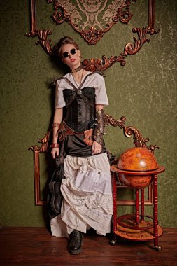 Victoria döneminden kalma iç mimarisi olan bir odada duran güzel bir steampunk bayanın tam boy portresi. Steampunk dünyası. 