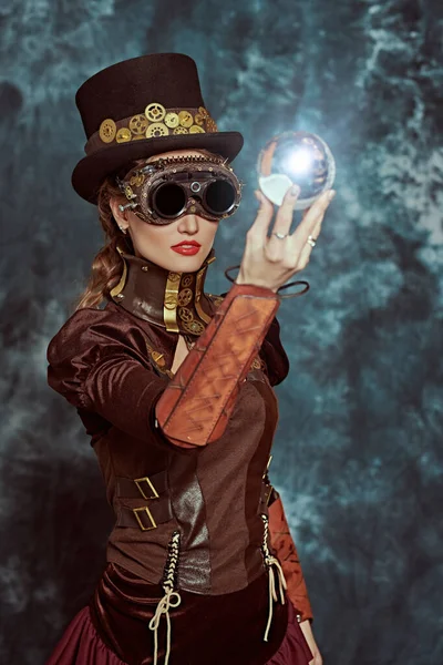 Victoria döneminden kalma güzel bir steampunk bayan, arka planda enerji kristali topunu tutuyor. Fantezi dünyası, bilimsel icatlar.