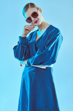 Yaz stili. Mavi elbiseli ve şık güneş gözlüklü güzel bir kadının portresi. Gözlük modası. 