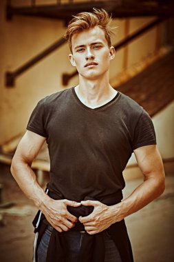 Şehrin eski semtinde, günlük giysiler içindeki yakışıklı genç adam sokakta duruyor. Kentsel grunge tarzı. 