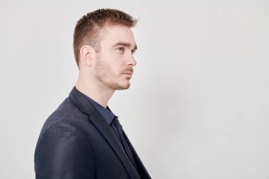 Yakışıklı, olgun bir adam beyaz arka planda koyu mavi bir takım elbiseyle poz veriyor. Erkek güzelliği, moda. İş stili. Boşluğu kopyala.