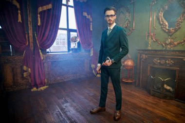 Yakışıklı ve saygıdeğer bir adam. Lüks bir dairede bastonuyla duran zarif klasik takım elbiseli yakışıklı bir adamın tam boy portresi. Erkek güzelliği, moda.