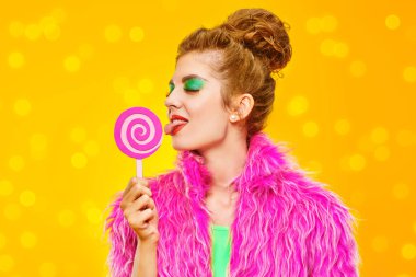 Renkli giysiler içinde, üzerinde lolipop olan göz kamaştırıcı, modaya uygun bir model. Sarı bir arka plan. Aktif, parlak yaşam tarzı. Boşluğu kopyala.