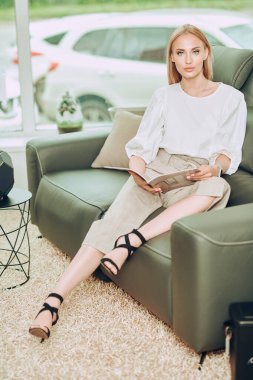 Zarif bir iş tarzı. Güzel genç bir kadın modern bir iç mekanda deri bir koltukta oturuyor. Mobilya ve iç dekorasyon.