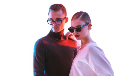 Moda stüdyosu çekimi. Yakışıklı genç adam ve güzel genç kadın şık gözlüklerle birlikte poz veriyorlar. Optik biçimi.