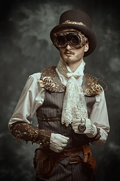 Fantasy world, scientific inventions. Portrait of a handsome victorian steampunk man on a grunge background.