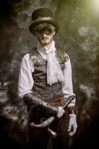Portrait of a courageous victorian steampunk man standing with a gun on a grunge background. Fantasy world, adventures.