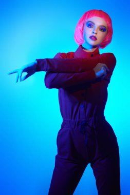 Makyaj malzemeleri ve saç stili. Parlak parlak makyajlı ve pembe saçlı güzel bir kadının portresi. Renkli ışıkta poz veriyor. Güzellik eğilimleri. 