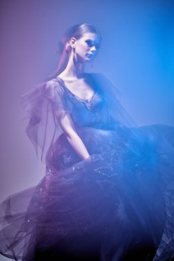 Güzel manken kız lüks bir gece elbisesi içinde hareket halinde duruyor. Moda ve güzellik konsepti. Stüdyo resmi.