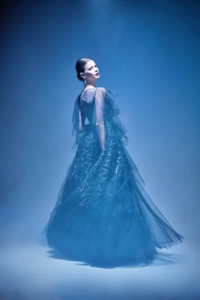 Evening fashion. Beautiful graceful girl poses in a luxury evening dress in a motion. Full length studio portrait.