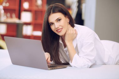 Yaşam tarzı. Samimi stüdyo dairesindeki yatağında dizüstü bilgisayar kullanan güzel bir kadının portresi. Evin içi, mobilyalar..