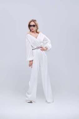 Lüks bir yaşam tarzı. Beyaz arka planda stüdyoda poz veren şık takım elbiseli ve takılı çekici orta yaşlı bir kadının tam boy portresi. Moda fotoğrafı.. 