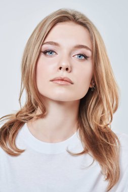 Sarışın ve doğal makyajlı güzel bir genç kadının portresi. Beyaz bir arka planda stüdyo çekimi. Güzellik endüstrisi.