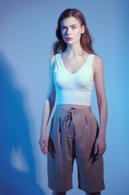 Stüdyoda yaz kıyafetleriyle poz veren sarışın güzel bir genç kadının portresi. Güzellik, moda çekimi..