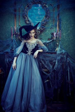 Sihirli Cadılar Bayramı. Cadı kostümlü güzel genç kadın eski kaledeki şöminenin yanında duruyor. Kutlama. Cadılar Bayramı partisi. 