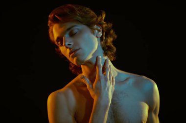 Güzel sarı saçlı, siyah arka planda karışık renkli ışık şeklinde poz veren yakışıklı bir atletik adamın sanat portresi. Erkek güzelliği. Spor ve sağlıklı yaşam tarzı.