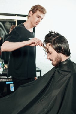 Berber dükkanında müşteriye hizmet eden kuaför. Yakışıklı esmer adam kuaför salonunu ziyaret ediyor..