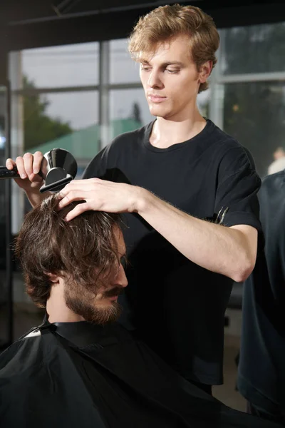 Hair Styling. Master barber does the hairstyle and styling with dryer, dries hair to a handsome male client. Barbershop.