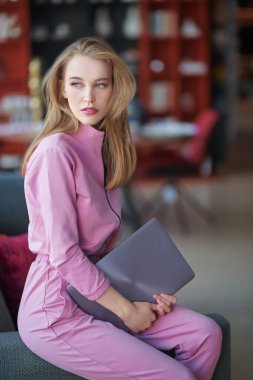 Kendine güvenen genç bir kadın evdeki laptopuyla koltukta oturuyor. İş konsepti. 