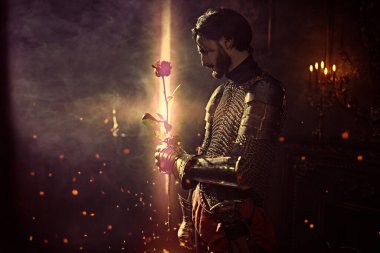 Romantizm çağı. Zırhlı asil bir şövalyenin portresi elinde kırmızı bir gülle bir kalede duruyor..