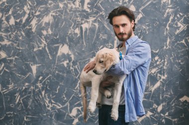 Bir adam ve bir evcil hayvan. Golden Retriever köpeğini kucaklayan genç bir adamın portresi.. 