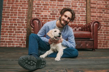 Mutlu genç adam evcil köpeği Golden Retriever ile oynuyor..