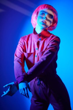 Makyaj malzemeleri ve saç stili. Parlak parlak makyajlı ve pembe saçlı güzel bir kadının portresi. Renkli ışıkta poz veriyor. Güzellik eğilimleri. 