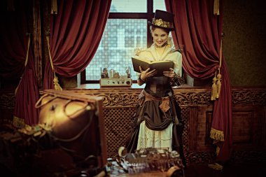 Güzel steampunk kadın bilim adamı laboratuarında duruyor ve bir kitap okuyor. Viktorya döneminden kalma iç mimari. 