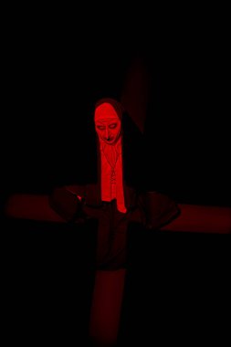 Scary devilish possessed nun with a cross in her hands kneels and prays standing in a dark room. Horrors and Halloween. clipart