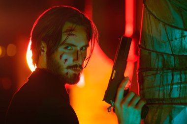 Yakışıklı, yaralı bir özel ajanın portresi. Şehrin arka sokağında elinde silahla tetikte bekliyor..