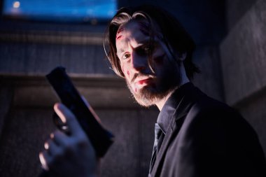 Yaralı bir aksiyon kahramanının yakın plan portresi. Gece şehrin ışığında elinde silahla bir kahraman.. 