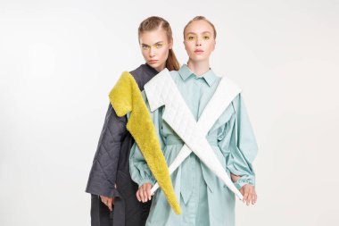 İki manken kız bahar-yaz koleksiyonundan şık kıyafetler giyip poz veriyor. Moda modası. Beyaz arkaplanda stüdyo portresi.