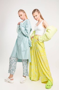Romantic summer style. Two beautiful fashion models girls pose in elegant summer clothes and clogs. Full length studio portrait on a white background. Fashion.  clipart