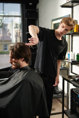 Berber berber dükkanında çalışıyor. Koyu saçlı, sakallı ve bıyıklı yakışıklı adamın kuaför salonunda saç kesimi var.. 