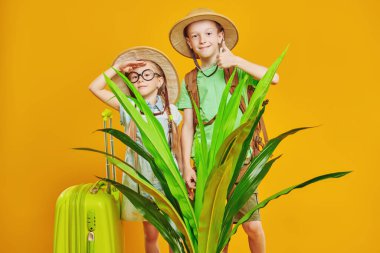 Neşeli çocuklar bir yolculuğa çıkar. Yaz tatili, turizm. Çocukların hayalleri ve hayalleri. Sarı arka planda stüdyo resmi.