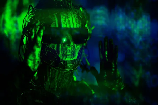 Close up portrait of a cyberpunk warrior wearing sunglasses and with wires on his head in neon night green light. World of the future. Game, virtual reality.