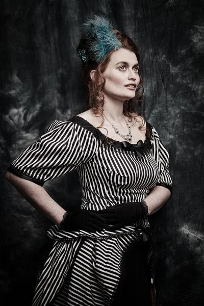 Portrait of a beautiful red-haired woman in a 19th century dress on a vintage background. Fashion history, makeup and hairstyle.