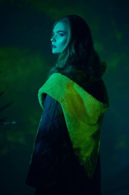 Şık ceketli güzel bir kızın portresi stüdyoda sarı ve yeşil ışıkta poz veriyor. Moda koleksiyonu. Özel tasarım kıyafetler.. 