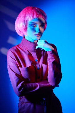 Makyaj malzemeleri ve saç stili. Parlak parlak makyajlı ve pembe saçlı güzel bir kadının portresi. Renkli ışıkta poz veriyor. Güzellik eğilimleri. 