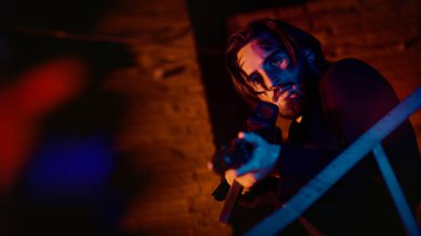 Gece vakti kırmızı ve mavi ışıkta sanayi bölgesinde otomatik silahlı cesur aksiyon kahramanı. Yakışıklı yaralı adam.. 