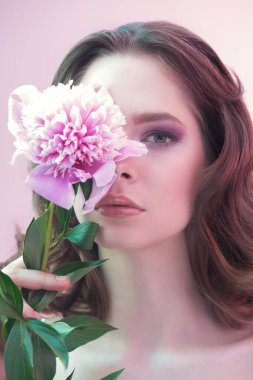Güzellik, parfüm ve kozmetik. Narin leylak-menekşe makyajlı güzel bir kadının portresi. Elinde narin bir şakayık çiçeği var.. 