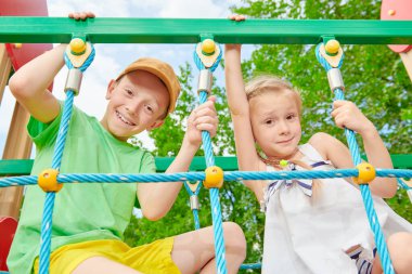 İki mutlu çocuk dinleniyor ve parkta oyun parkında eğleniyorlar. Yaz tatili. Mutlu çocukluk.