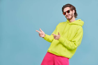 Yan tarafı gösteren çekici genç bir adam. İnsanlar, duygular. Reklamcılık. Daireli mavi bir arkaplanda stüdyo portresi.