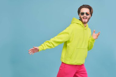 Çekici genç adam stüdyoda hareket halinde poz veriyor. İnsanlar, duygular. Reklamcılık. Daireli mavi bir arkaplanda stüdyo portresi.