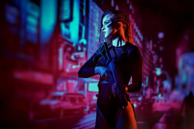 Geleceğin güzel siber savaşçısı otomatik bir silahla neon ışıklarının arasında tetikte bekliyor. Geleceğin dünyası. Oyun, sanal gerçeklik.