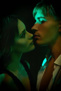 Yeşil ışıkta birbirine bakan tutkulu bir adamla seksi bir kadının yakın plan portresi. Aşk konsepti.
