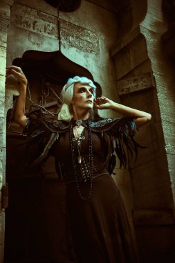 Güzel gri saçlı ve zengin siyah elbiseli aristokrat bir dul kadın mezarlıktaki bir mahzende poz veriyor. Kara Dul. Gizemciliğin atmosferi. Cadılar Bayramı.